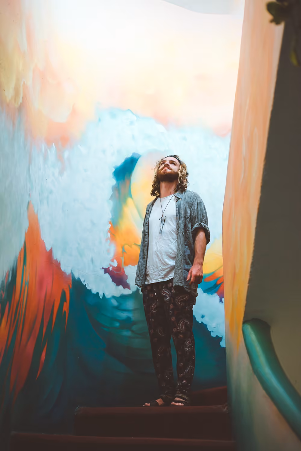 A man standing in front of a colourful wave mural