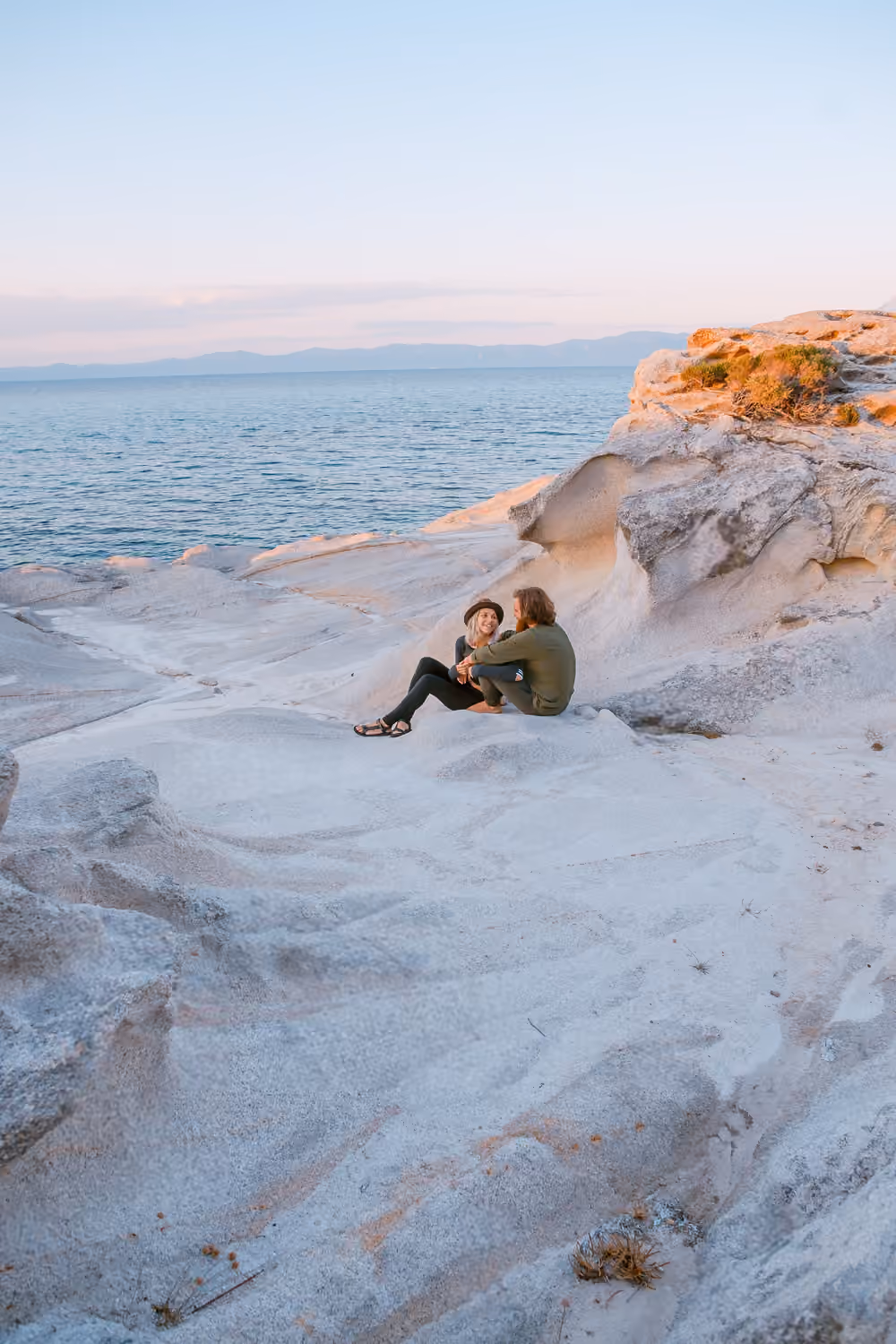Two travellers sitting on white rocks by the sea
