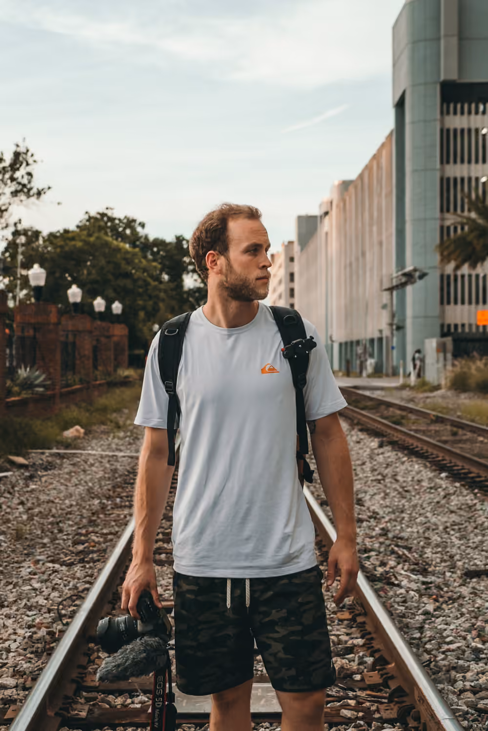 A man with a backpack standing on a railway track