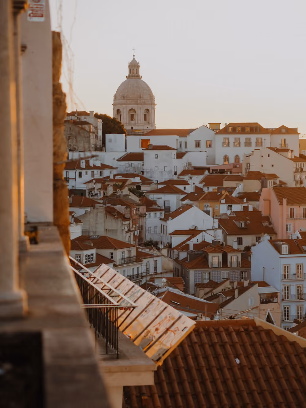 Lisbon rooftops and a church dome in warm evening light